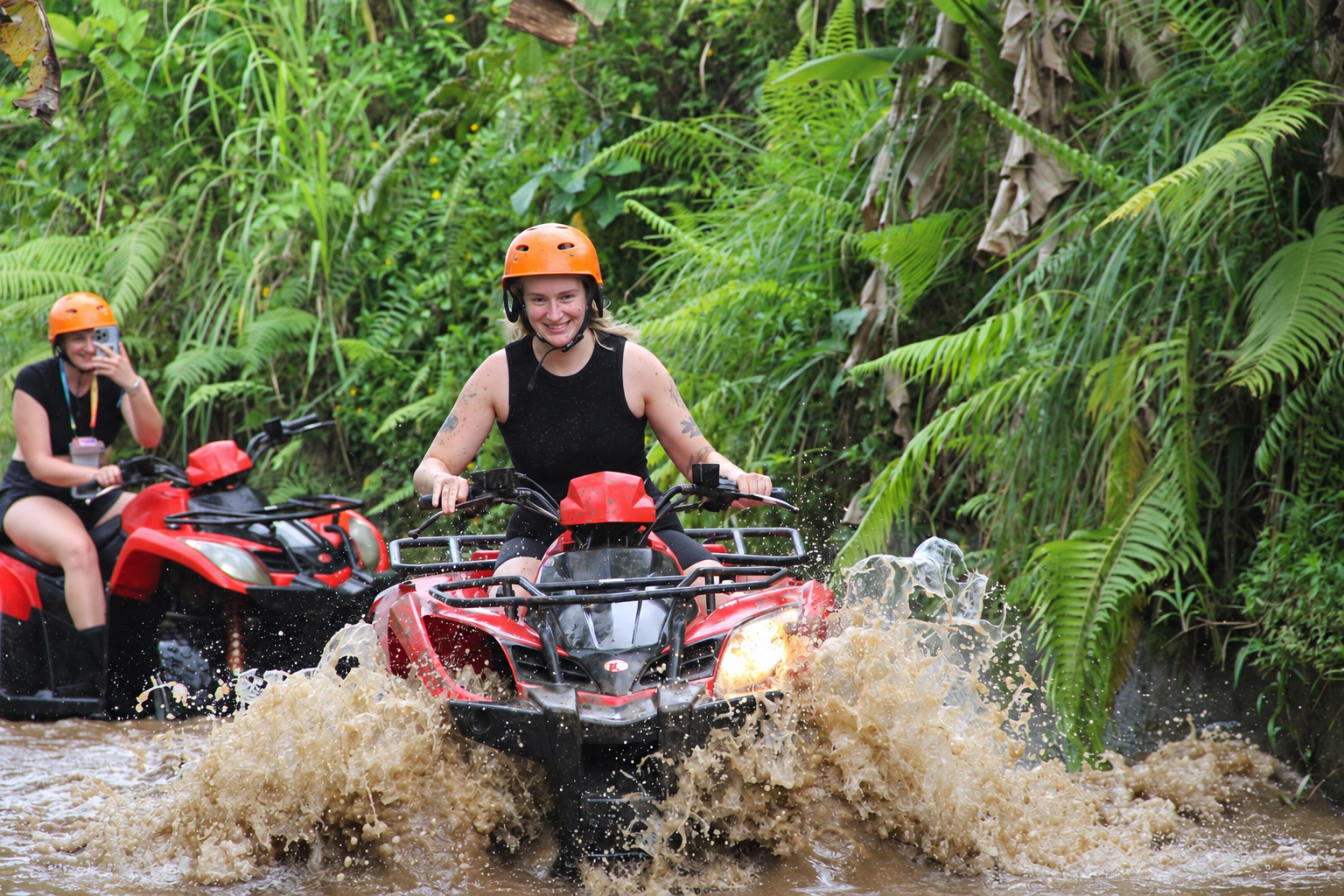 ATV rider splashing through a jungle trail