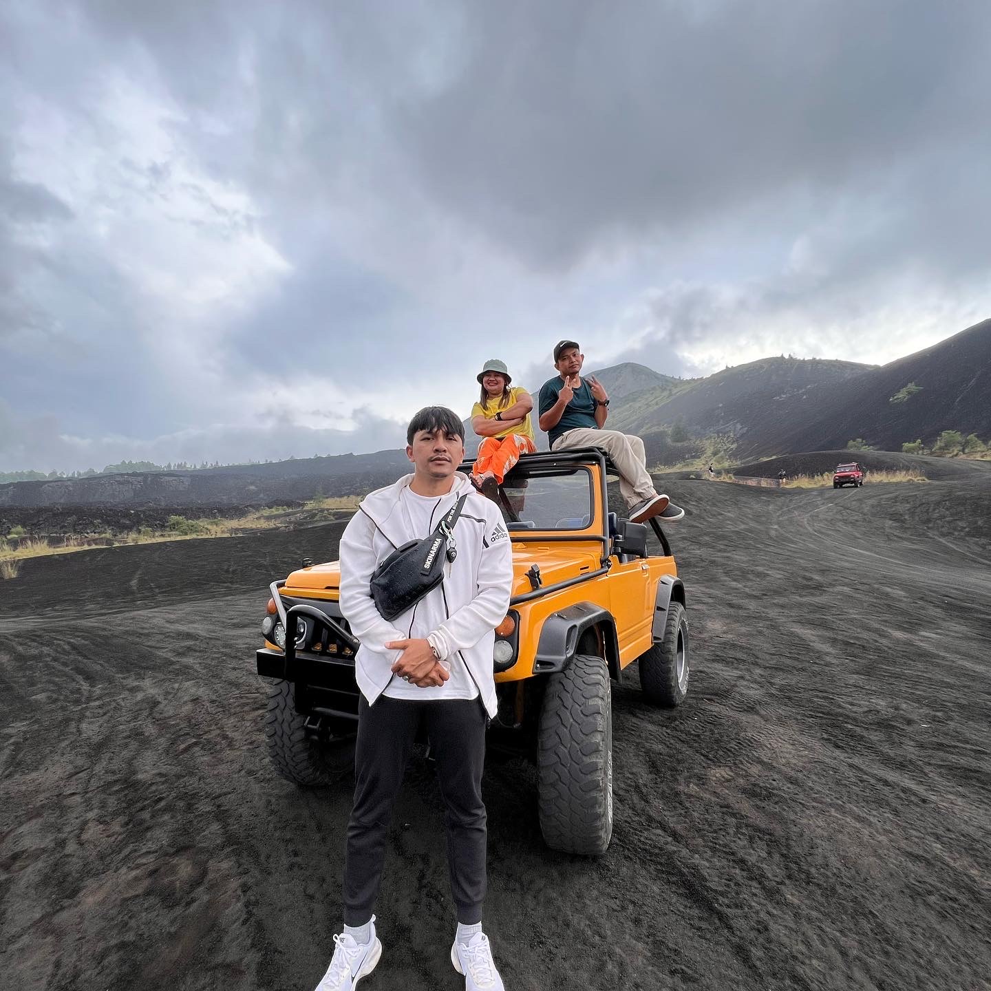 Travellers with a yellow jeep on Kintamani black sand