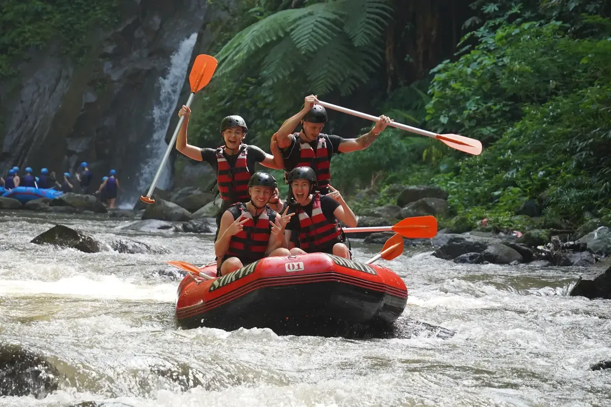 Rafting group on a tropical river beside a waterfall