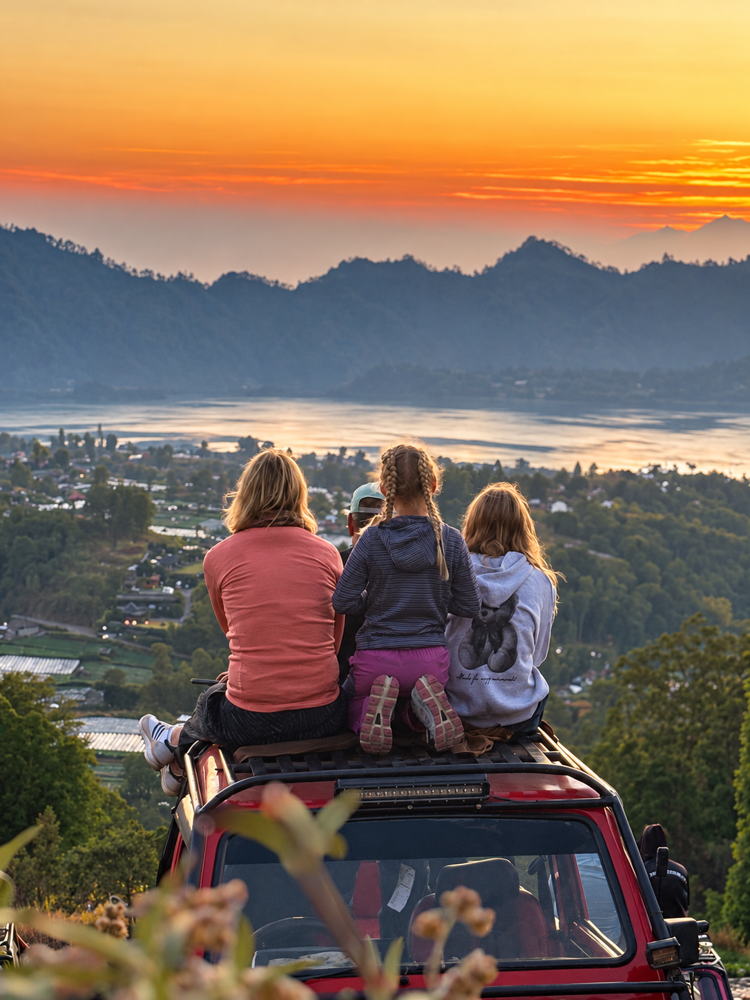 Guests sitting on a red jeep overlooking the lake at sunrise
